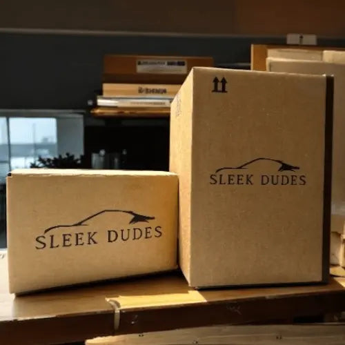 Two cardboard boxes with 'Sleek Dudes' branding on a wooden surface.