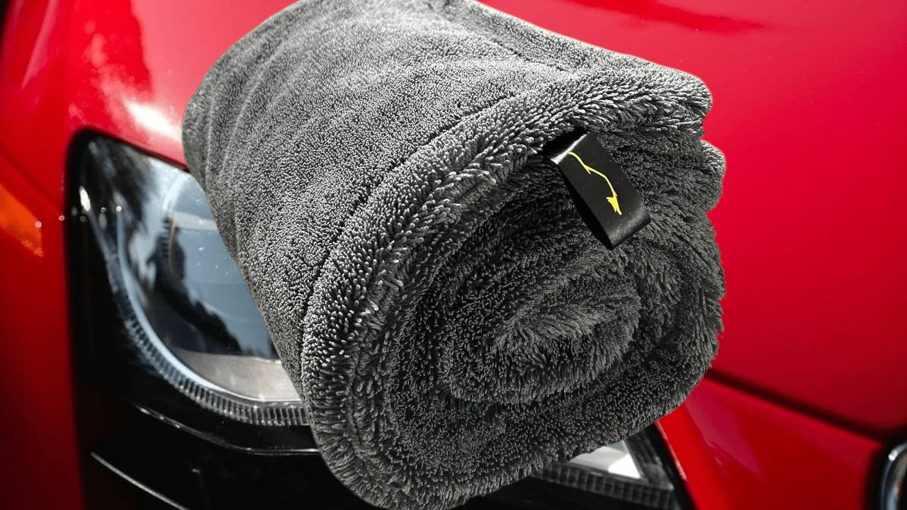 Rolled Sleek Dudes Sleek Max Dry 2K microfiber car drying towel on red car hood – ultra-absorbent 2000GSM towel for scratch-free automotive detailing.