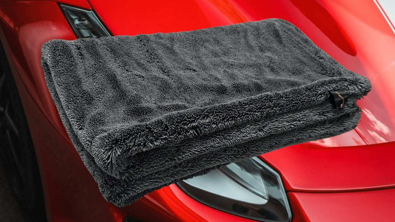 2000GSM black microfiber car drying towel on red sports car hood, showing plush double twist pile texture