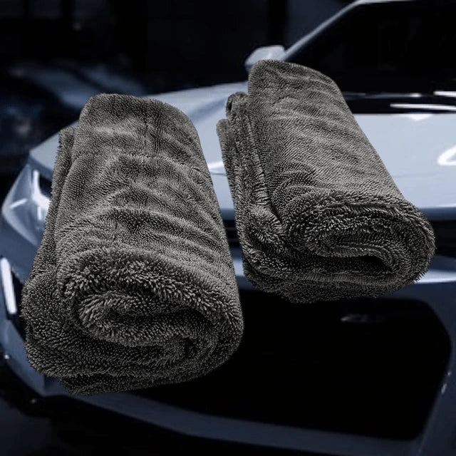 2 rolled microfiber car drying towels – Double Trouble by Sleek Dudes – in front of a white car.