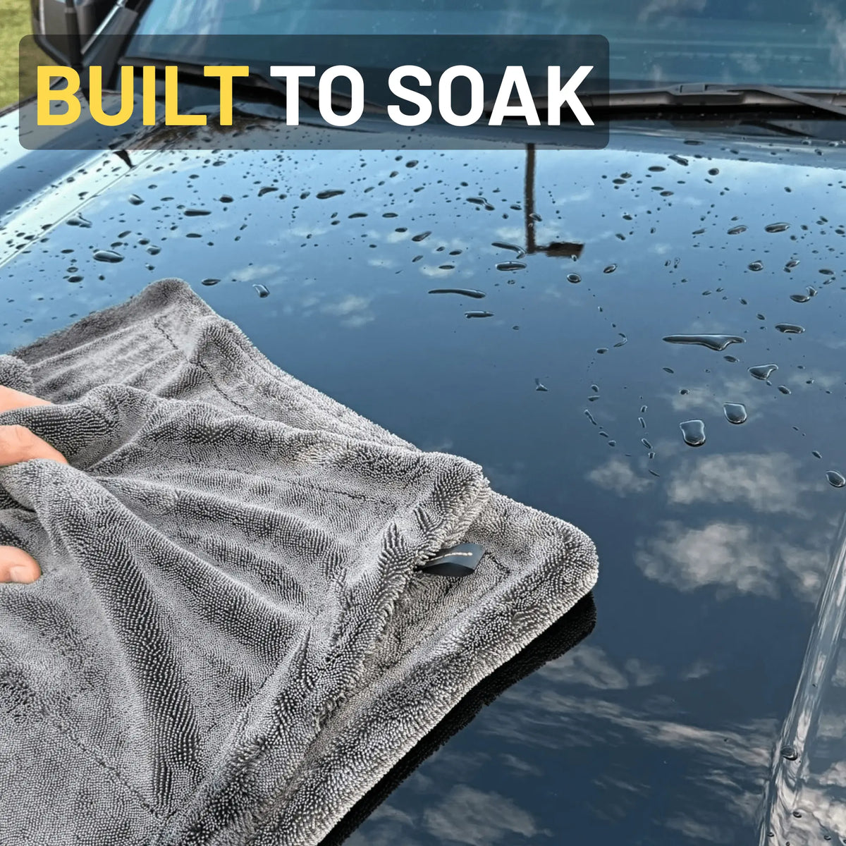 Grey car drying towel on a black car hood, saying built to soak on top