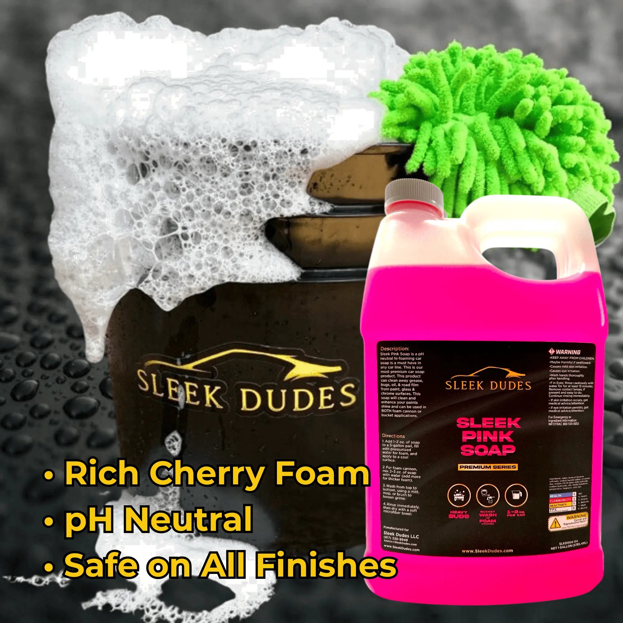 Pink bottle of 'Sleek Dudes' car care product with foam and green detailing cloth on a black surface.