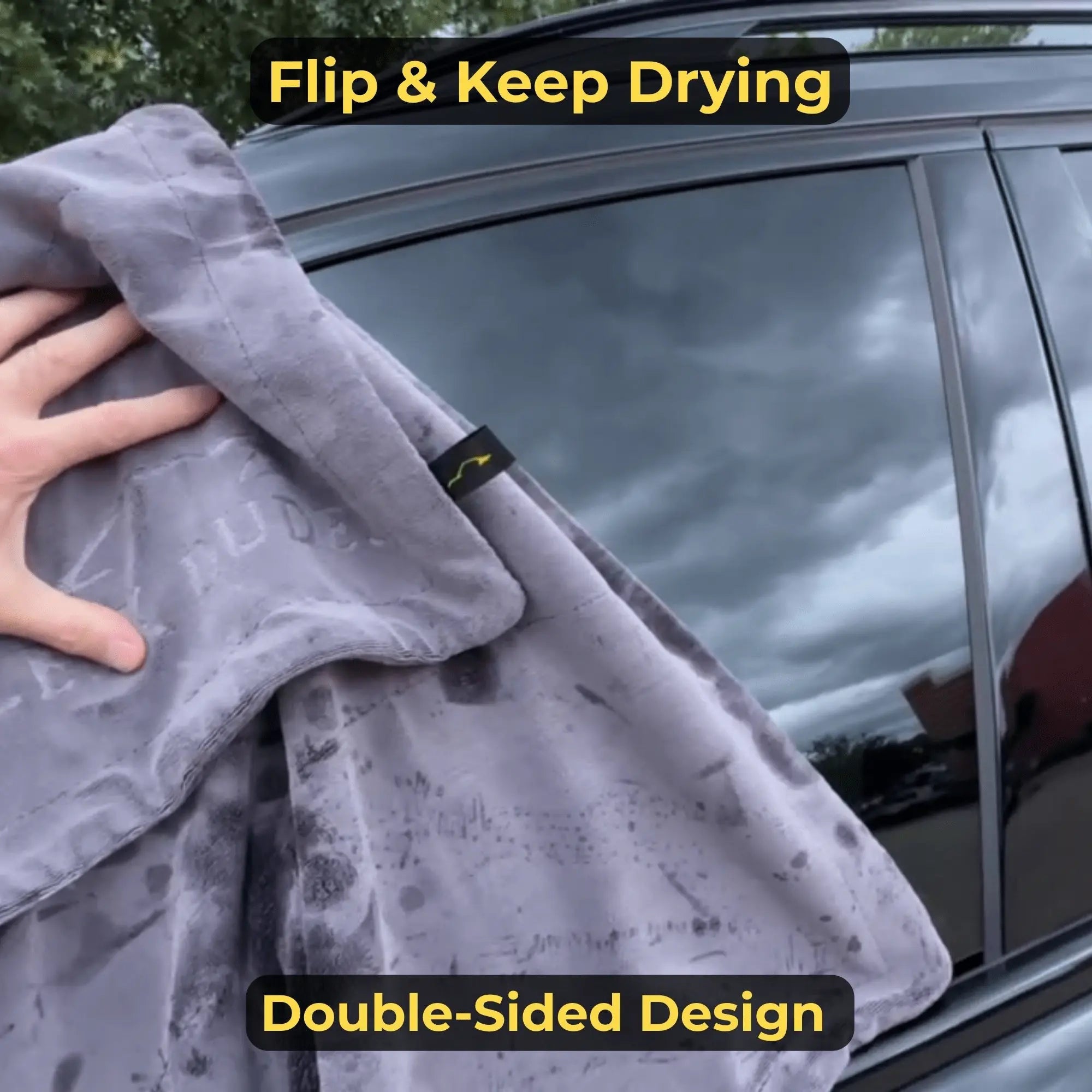 Person using a gray towel to dry a car window with text indicating 'Flip & Keep Drying' and 'Double-Sided Design'.