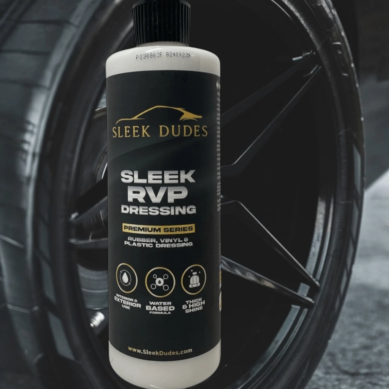 Sleek Dudes RVP Dressing bottle in front of a black wheel, used for rubber, vinyl, and plastic care.